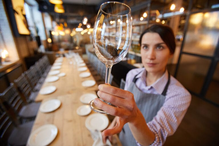 Bedienung im Restaurant kontrolliert ob das Glas schlierenfrei ist